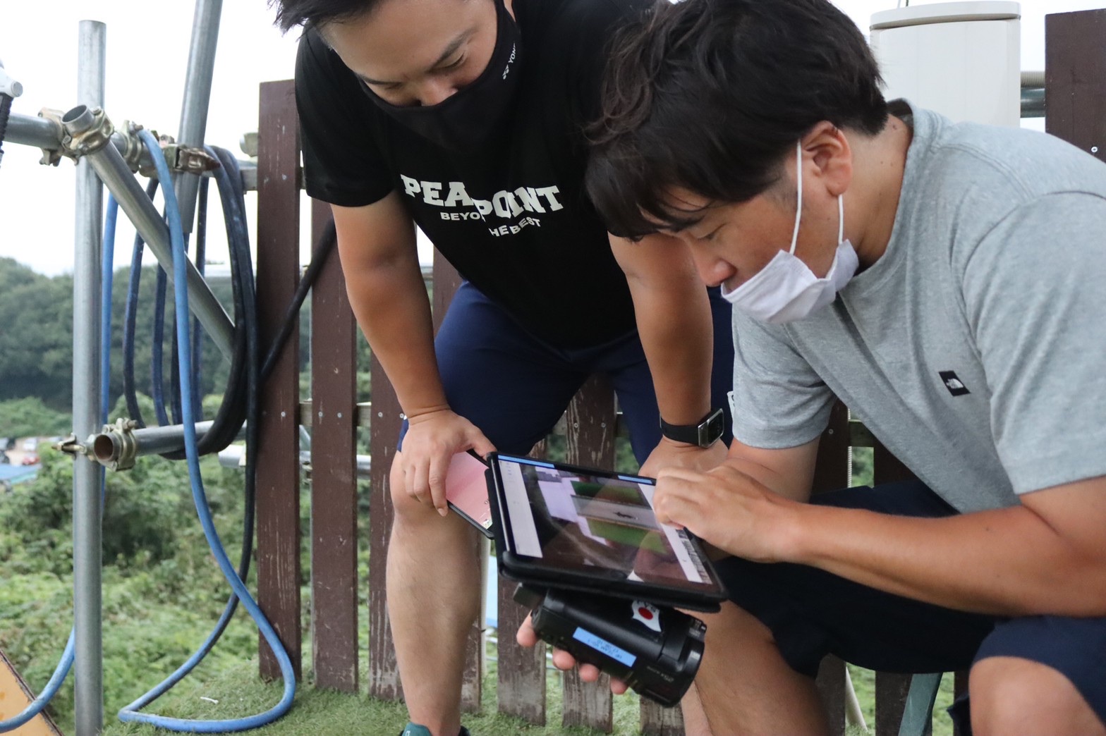 映像チェックする村上コーチと白川トレーナー